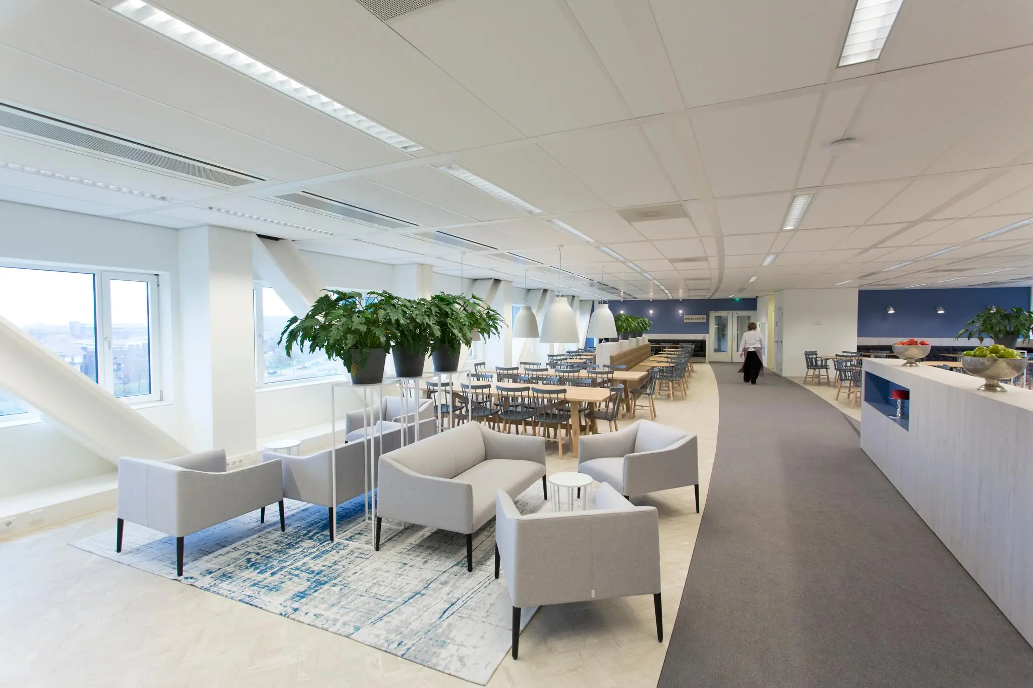 Moderne en lichte bedrijfsrestaurantinrichting aan het Rivium Boulevard met zitgedeelte, eettafels en groene planten.